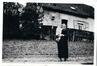 Photo Madame Hofman avec un jeune enfant dans les bras devant une maison au lieu-dit Beekkant (Molenbeek-Saint-Jean), photogr. anon., s.d.<br>